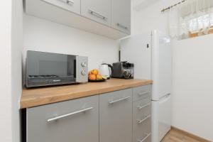 een keuken met witte kasten en een aanrecht met een magnetron bij Pet-Friendly Apartment Pańska with AC by Renters in Warschau