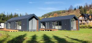 a black house in a field with a house at Chyża Zagroda in Jaworki