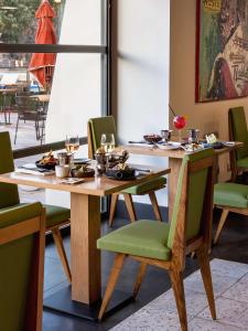 a dining room with a wooden table and green chairs at New Hotel of Marseille - Vieux Port in Marseille