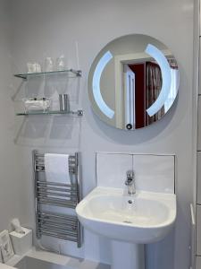 Baño blanco con lavabo y espejo en Gladstone House, en Edimburgo