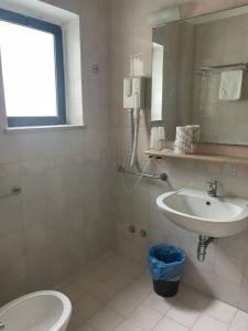 un bagno con lavandino, water e specchio di Hotel Piccolo Paradiso Del Gargano a Rodi Garganico