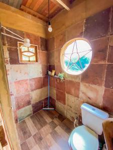 a bathroom with a toilet and a window at Casinha Terra Mística no Vale do Capão in Palmeiras