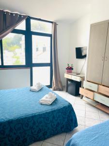 a bedroom with a bed and a desk and a window at HOTEL IL PICCOLO PARADISO DEL GARGANO in Rodi Garganico