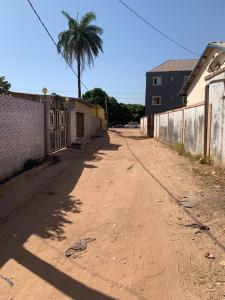eine unbefestigte Straße mit einer Palme und einem Gebäude in der Unterkunft Marie's residence in Medina Suware Kunda