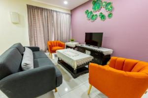 a living room with a blue couch and orange chairs at HyperTribe -Pangkor Holiday Home in Kampong Sungai Udang