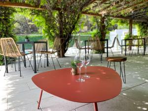 - une table rouge avec deux verres à vin dans l'établissement ibis Nîmes Ouest - A9, à Nîmes