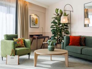 ブリュッセルにあるソフィテル ブリュッセル ヨーロッパのリビングルーム(緑の椅子2脚、テーブル付)