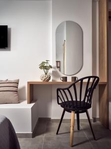 a bedroom with a black chair and a mirror at Cassiopeia Rooms & Suites in Laganas