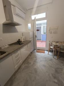 cocina con armarios blancos, mesa y ventana en Santos, en Málaga