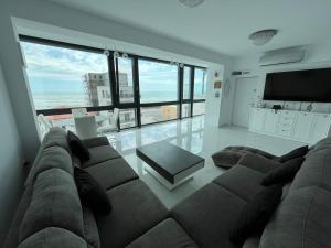 a living room with a large couch and a television at Luxury apartment with sea view in Mamaia Sat/Năvodari