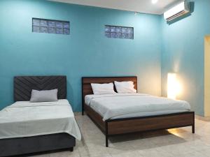 Duas camas num quarto com uma parede azul em Loven Sanur Guest House em Sanur