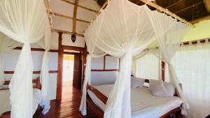 1 dormitorio con 2 camas con cortinas blancas en Kazinga Wilderness Lodge, en Katunguru