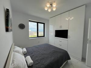 a white bedroom with a bed and a television at Luxury apartment with sea view in Mamaia Sat/Năvodari