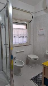 baño blanco con aseo y ventana en Appartamento Fiume, en Villasimius