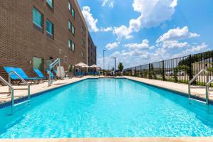 a swimming pool with chairs next to a building at La Quinta Inn & Suites by Wyndham Round Rock near Kalahari in Round Rock