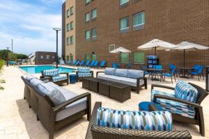 a patio with chairs and tables and a pool at La Quinta Inn & Suites by Wyndham Round Rock near Kalahari in Round Rock