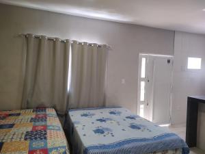 - une chambre avec un lit, un rideau et une porte dans l'établissement Maravilhoso loft beira mar, à Japaratinga