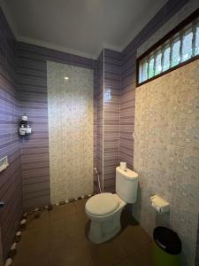 a bathroom with a toilet and a window at Pondok Damai Sidemen in Sidemen