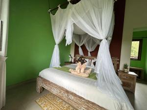 a bedroom with a canopy bed with two dolls on it at Pondok Damai Sidemen in Sidemen