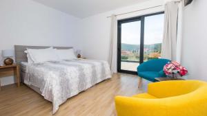 a bedroom with a bed and a chair and a window at Stylish villa near Dubrovnik with a swimming pool in Mlini +22 photos