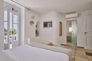 a white bedroom with a bed and a window at Myconian Princess in Mikonos