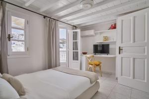 a white bedroom with a bed and a desk at Myconian Princess in Mikonos