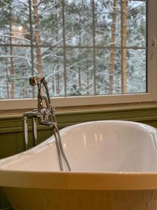 a bath tub with a water faucet in front of a window at Chata Paradise in Smižany