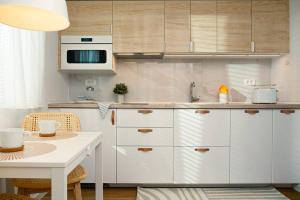 une cuisine avec des armoires blanches, une table et un micro-ondes dans l'établissement New Cute Studioapartment in Ljubljana + Free bikes, à Ljubljana