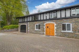 a brick house with a brown door on a brick driveway at Quirky Retreats - The Coach House in Windermere