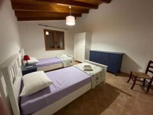 a bedroom with two beds and a table and a chair at Villa Marci con piscina privata a Nulvi (SS) in Nulvi