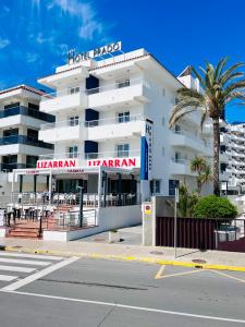 a hotel in front of a street with a palm tree at Hotel Arena Prado in Peniscola