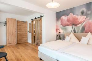 um quarto com uma cama branca e flores cor-de-rosa na parede em Gasthof Krone em Kinding