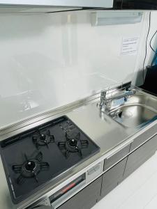 a kitchen counter with a stove and a sink at COAST西糀谷 in Tokyo