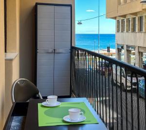 un tavolo con due tazze su un balcone con la spiaggia di NUOVO BILOCALE VISTA MARE a Savona
