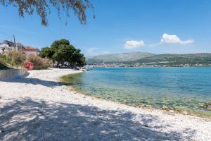 a beach with blue water and trees on the shore at Apartment Mali in Trogir