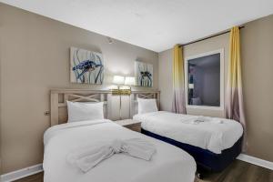 a room with two beds with white sheets and a window at Beachfront Condo in Atlantica Resort with Pool in Myrtle Beach +32 photos