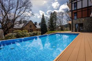 a large blue swimming pool next to a building at Green Park Resort A15- z dostępem do basenu, sauny, jacuzzi, siłowni in Szklarska Poręba