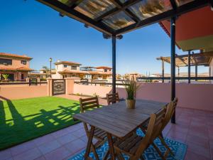 einen Holztisch und Stühle auf einer Terrasse in der Unterkunft Private Terrace Majanicho Home -Garden & Pool in La Oliva