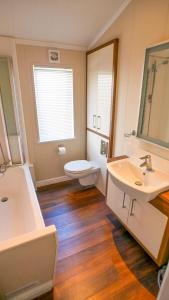 a bathroom with two sinks and a toilet and a mirror at Luxury 3 Bed 2 Bath Lodge with Sea Views! in Exmouth