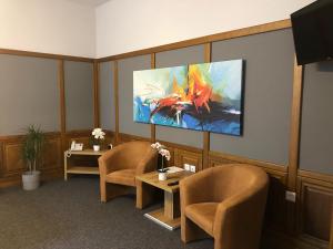 a waiting room with two chairs and a tv on the wall at Svájci Lak Panzió in Nyíregyháza