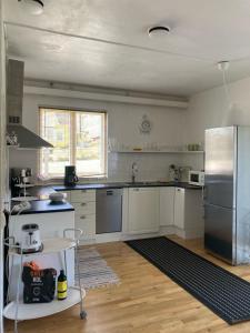 cocina con armarios blancos y nevera de acero inoxidable en Blankaholm nära marinan, en Blankaholm