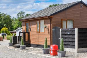 a small wooden house with a gate and a fence at Ivy Cabin with Hot Tub in York