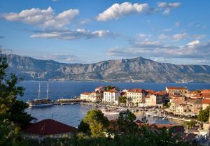 a town on the water with mountains in the background at Apartmani Vila Nela in Postira