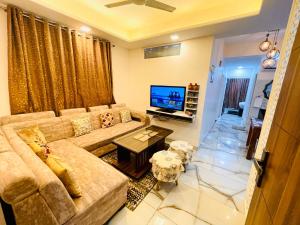 een woonkamer met een bank en een televisie bij 3BHK Airport Vista Apartment - Entire Apartment in Jaipur