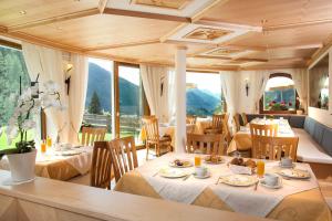 uma sala de jantar com mesas, cadeiras e janelas em Hotel Garni Aghel em Selva di Val Gardena