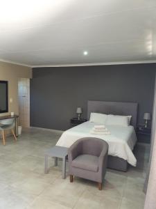 a bedroom with a large bed and a chair at Pro Plants Accommodation in Kimberley