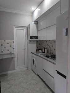 a kitchen with white cabinets and a washing machine at Holiday House Likani in Borjomi