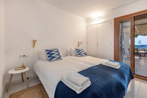 Dormitorio blanco con cama con almohadas azules y blancas en LA GOLA APARTMENT, First-line Beachfront, Newly Refurbished en Port de Pollensa