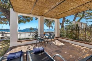un porche cubierto con mesa y sillas en LA GOLA APARTMENT, First-line Beachfront, Newly Refurbished, en Puerto Pollensa