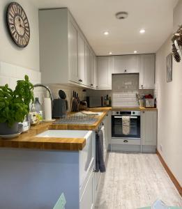 a kitchen with white cabinets and a clock on the wall at The Cabin, Roundabout Lane in West Chiltington